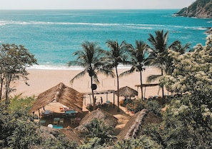 A beachside resort with thatched-roof huts, palm trees, and a view of the ocean. - Bahía de la Luna (San Pedro Pochutla)