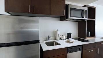 A modern kitchen with stainless steel appliances, dark wooden cabinets, and a white countertop.