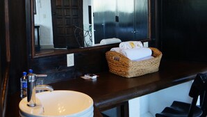 A bathroom with a large mirror, a round sink, a dark wooden vanity, and a wicker basket on the counter. - Hotel Casa Blanca San Miguel (San Miguel de Allende)