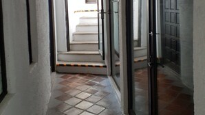 A hallway with tiled flooring, a staircase leading to an upper level, and a door with a glass panel. - Hotel Casa Blanca San Miguel (San Miguel de Allende)