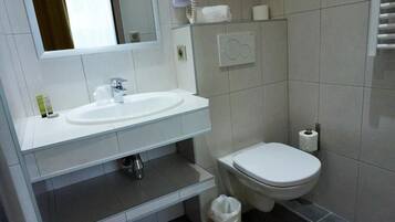A modern bathroom with a white sink, a toilet, and a mirror.