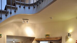 A spiral staircase with a stone wall and a red carpeted floor. - Hôtel de la Couronne (Aix-les-Bains)