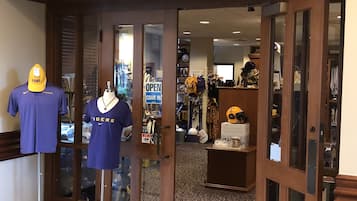 A gift shop named "John and Rose Ann Shelton Gift Shop" with mannequins displaying sports apparel and a sign indicating the shop is open.
