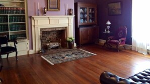 Una habitación con chimenea, una estantería, una mesa de comedor con sillas y un candelabro.