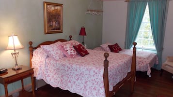 Una camera da letto con due letti, un comodino con una lampada, un quadro appeso al muro e una finestra con tende.