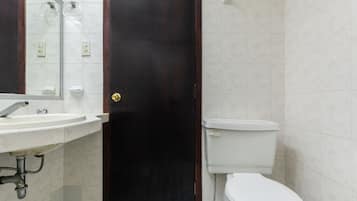 Ein Badezimmer mit einer dunkelholznen Tür, einer weißen Toilette und einem Waschbecken mit Spiegel darüber.