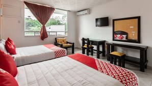 Habitación de hotel con dos camas, un escritorio, una silla, un televisor y una ventana con cortinas.