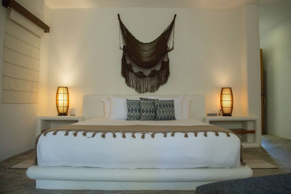 Un dormitorio con una cama grande, dos mesitas de noche y un adorno en la pared.