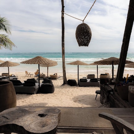 A beachside lounge with thatched umbrellas, lounge chairs, and a wooden deck overlooking the ocean.