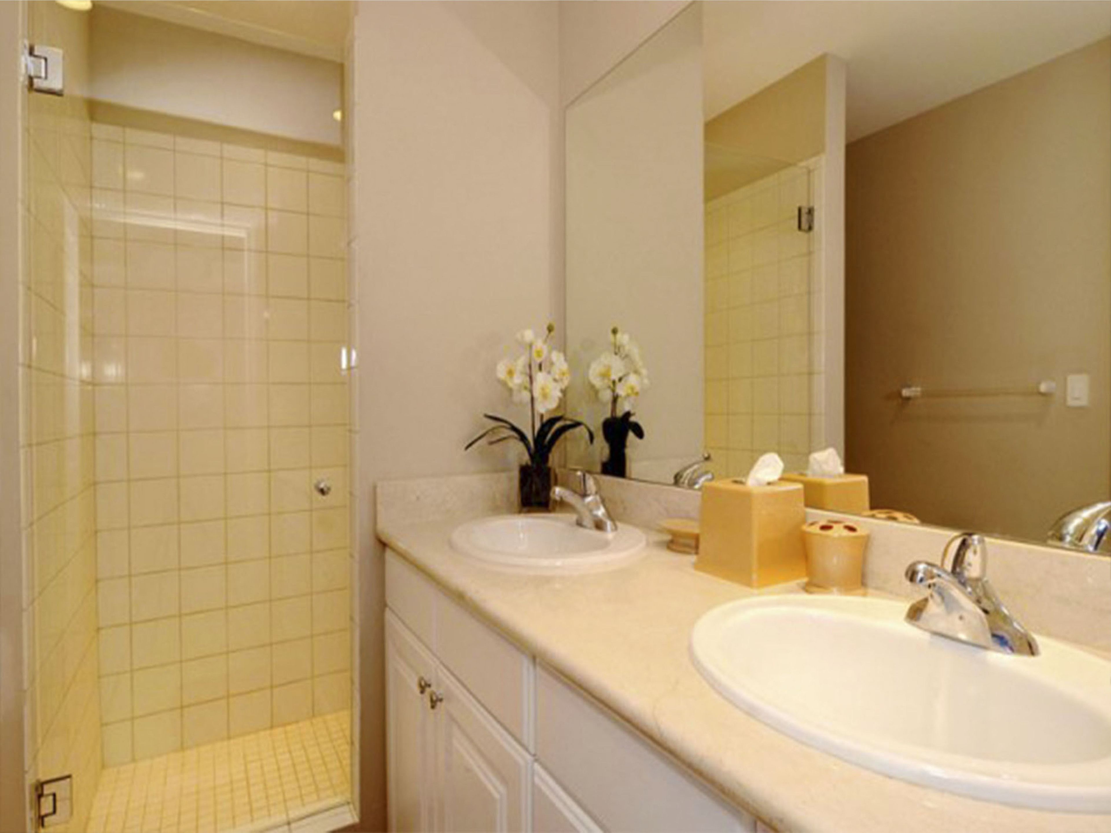 A bathroom with two sinks, a shower, and a mirror.