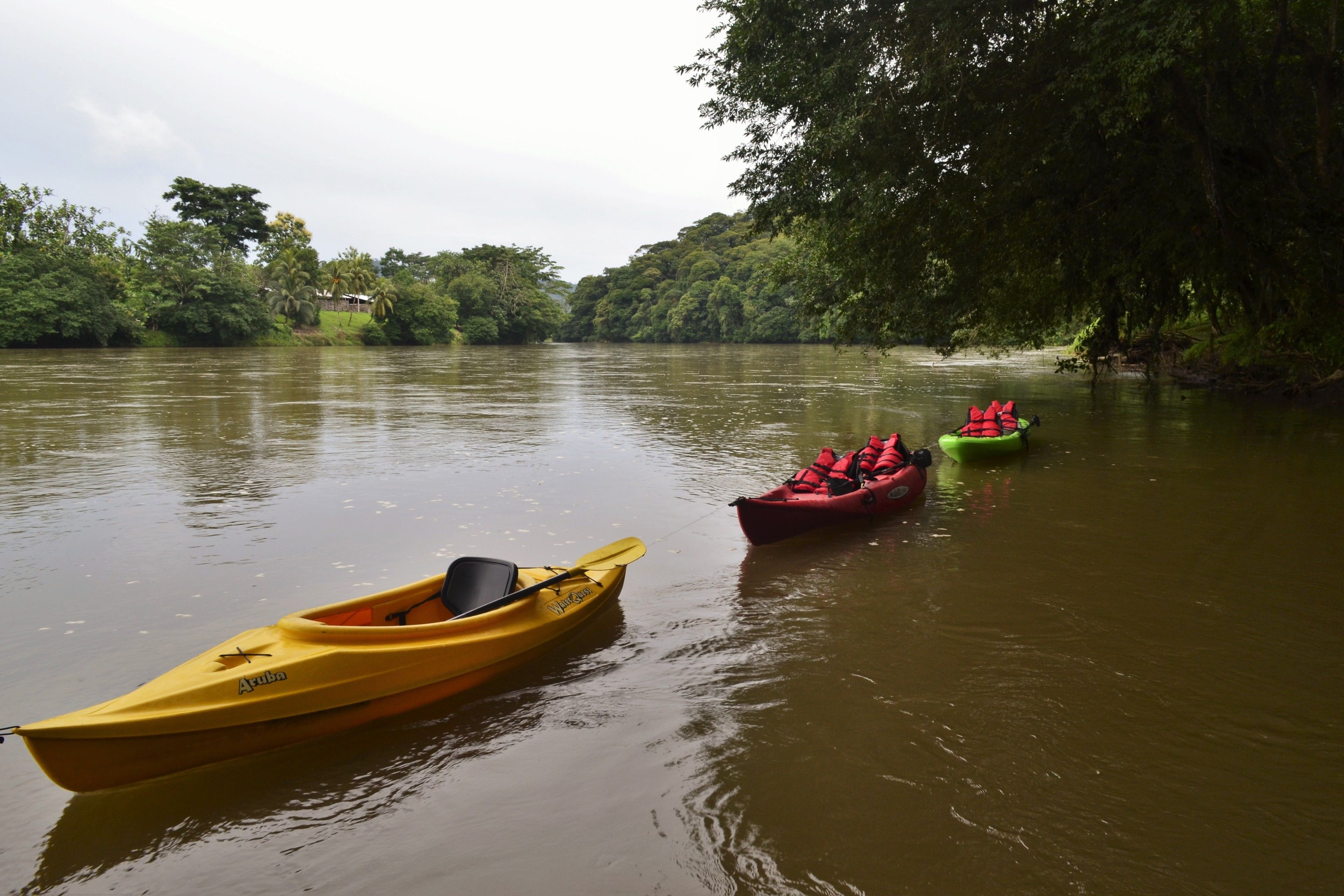 A calm river with kayaks and a yellow boat.