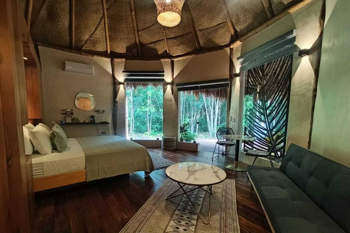 Quarto com cama, sofá, mesa redonda e vista para o exterior.