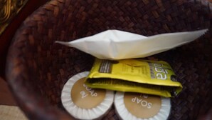 A woven basket containing soap bars and a folded paper airplane.