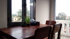 A wooden dining table with chairs, a potted plant, and a bag on it. - Luang Prabang Serviced Apartment (Luang Prabang)
