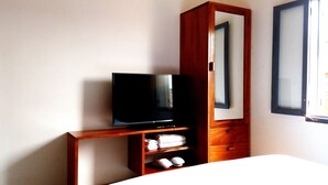 A hotel room with a TV on a wooden stand, a mirror, and a bed. - Luang Prabang Serviced Apartment (Luang Prabang)