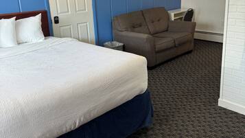 A hotel room with a bed, a couch, a door, and a window.