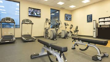 Un gimnasio con cintas de correr, elípticas y zona de pesas.