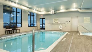 An indoor swimming pool with clear glass walls, a lifeguard station, and a view of parked cars outside. - Hampton Inn & Suites Minneapolis University Area (Minneapolis)