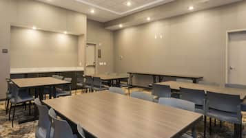 Ein Konferenzraum mit mehreren Tischen und Stühlen, einem teppichartigen Marmorbelag und einer Decke mit eingelassenen Leuchten.