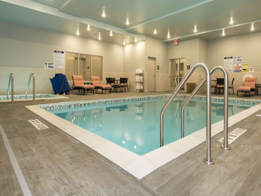 A swimming pool with a tiled deck, lounge chairs, and a lifeguard chair.