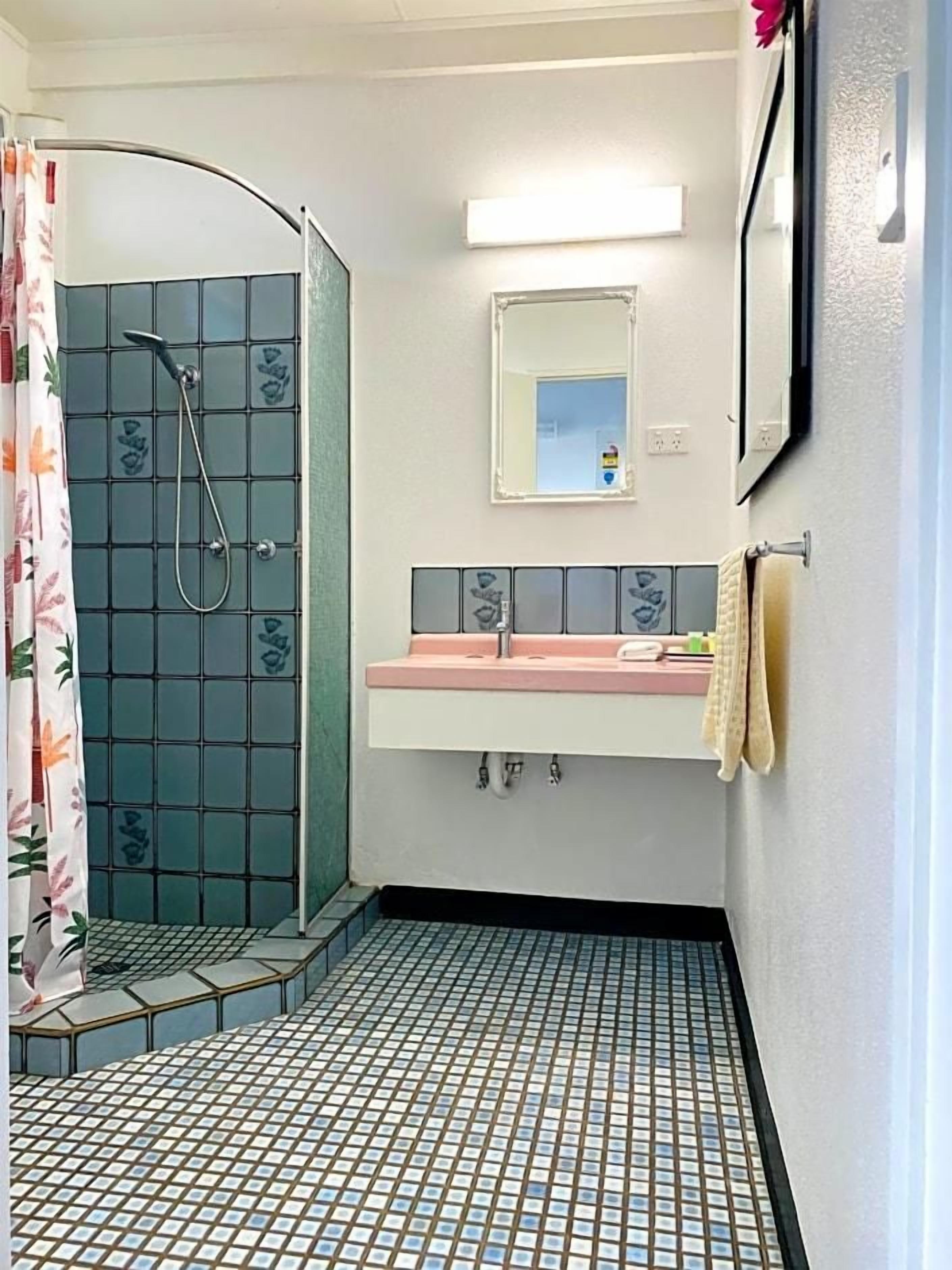 A bathroom with a shower, a sink, and a mirror.