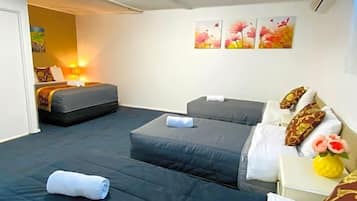 A hotel room with two beds, a bedside table with a vase, and a wall with three flower paintings.
