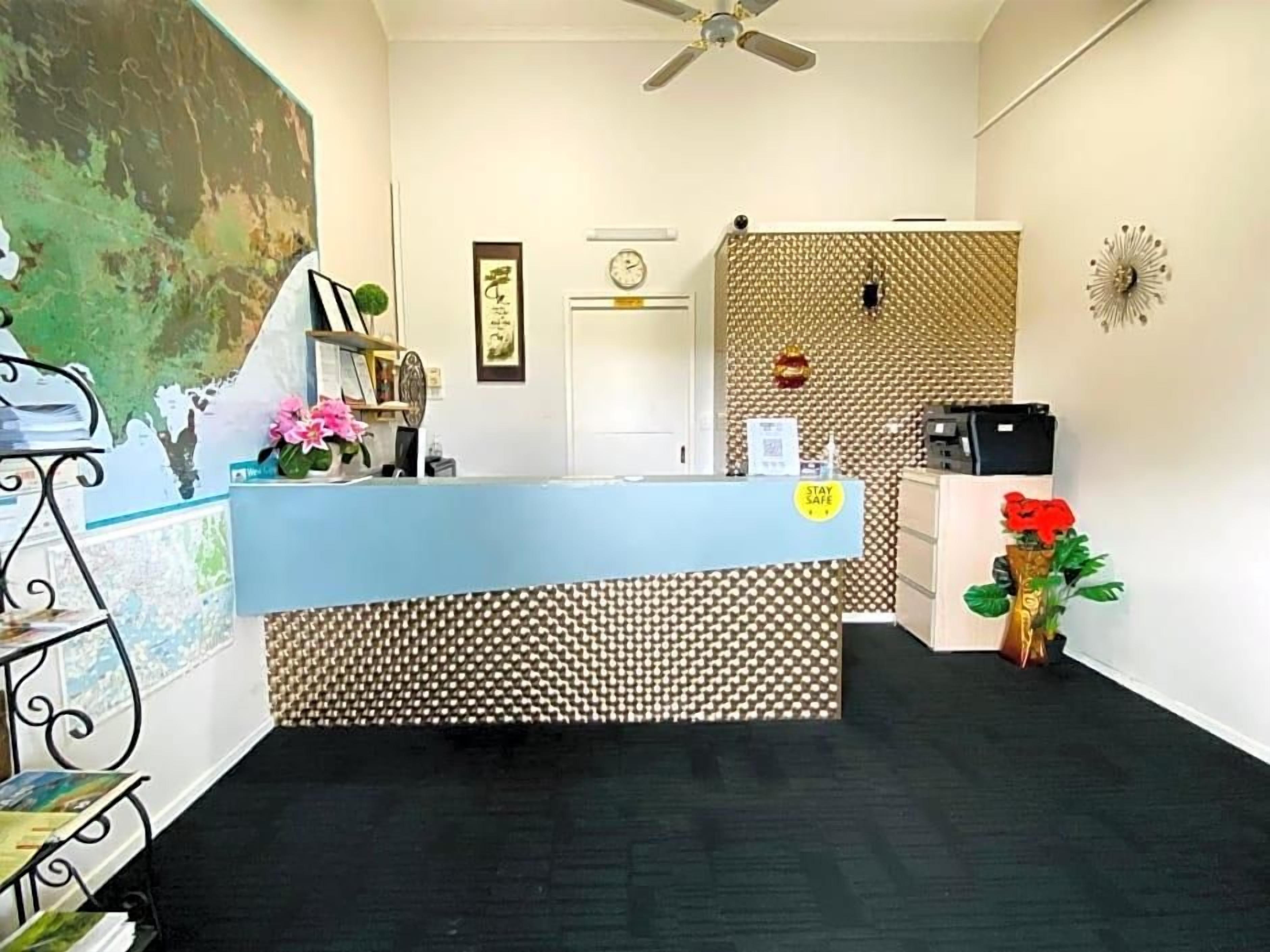 A reception area with a desk, a clock, and a wall with a geometric pattern.