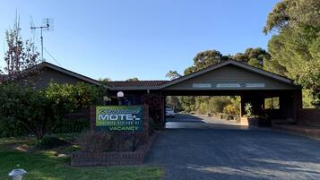 A Kingswood Motel with a 'VACANCY' sign, a covered entrance, and a driveway leading to the building.