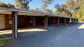A building with a covered outdoor area, brick walls, and a gravel ground.