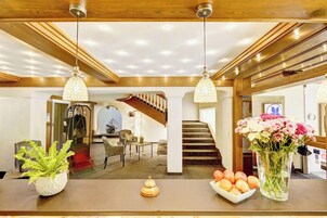 Un área de recepción con un mostrador de madera, un jarrón de flores y un frutero.
