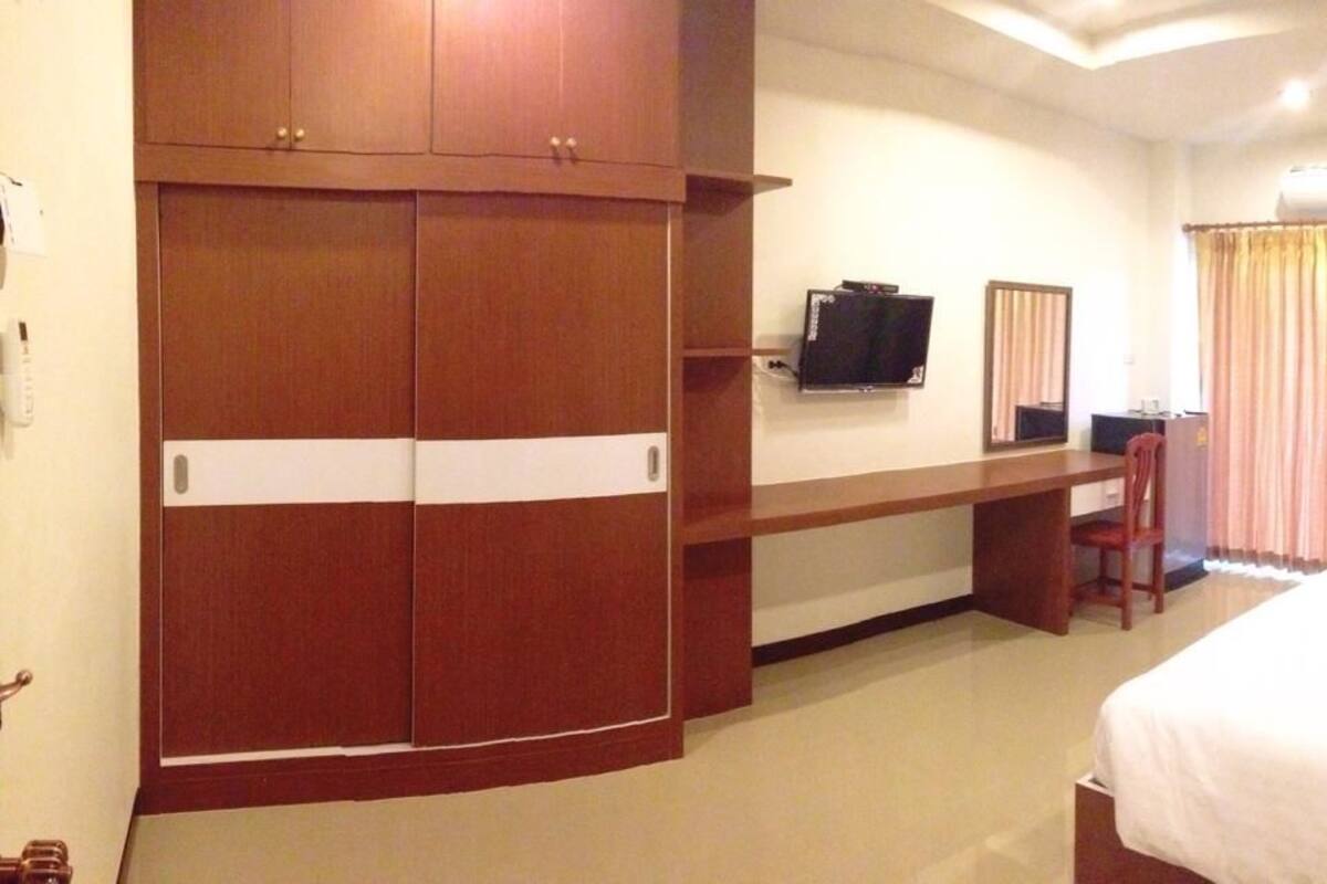 Habitación de hotel con cama, escritorio, televisor y armario.