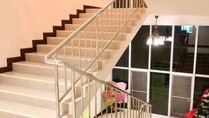 A staircase with a metal railing leading to a landing. - The Lion Residence (Surin)