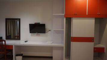 A room with a white desk, a television mounted above it, and a red and white wardrobe.