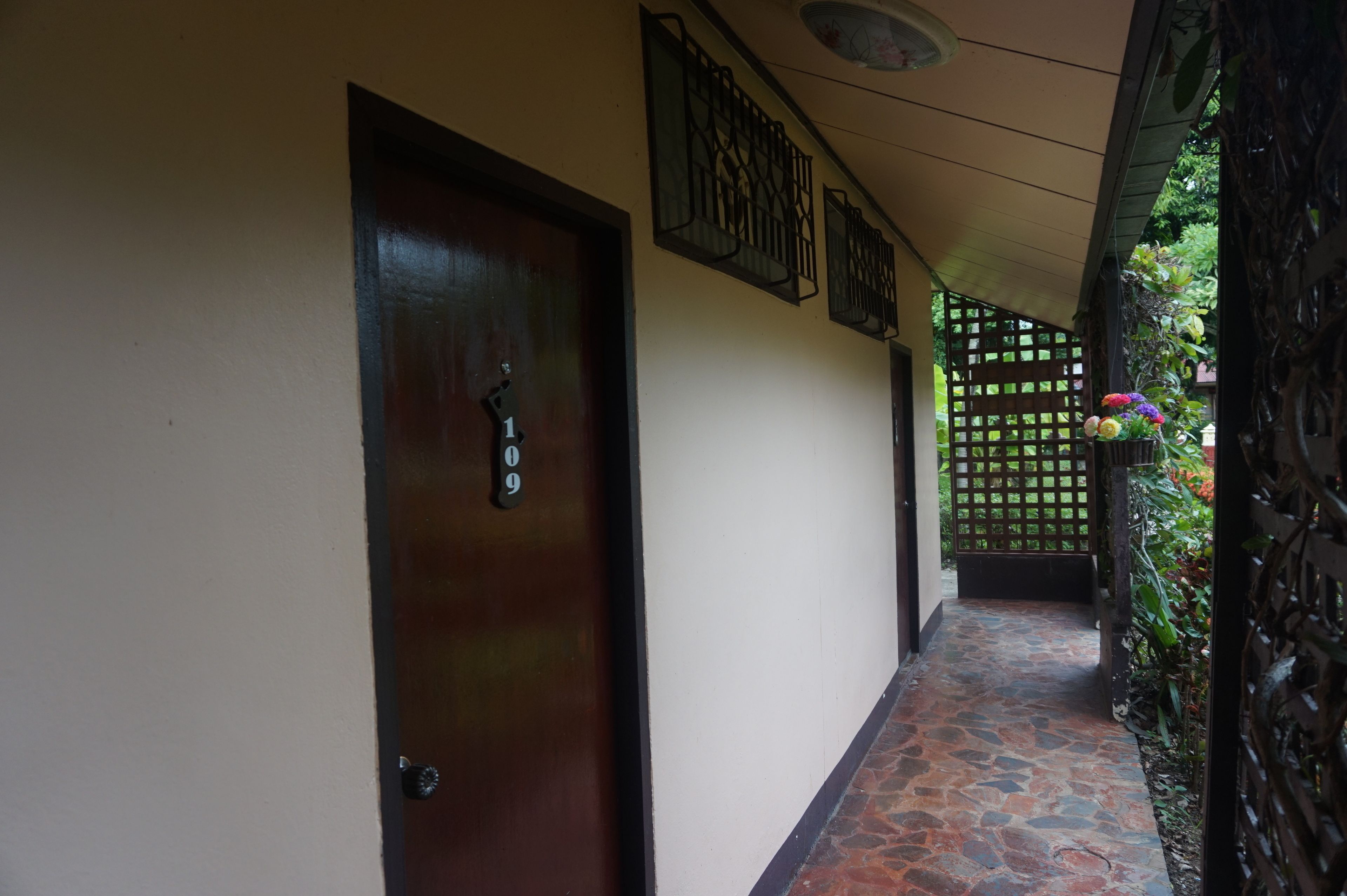 A hallway with a wooden door, a tiled floor, and a decorative wall panel.