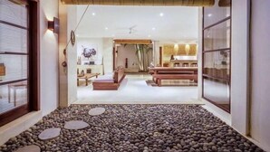 Un interior moderno con un sendero de piedra que conduce a una zona de estar y una cocina visible a través de un umbral abierto.