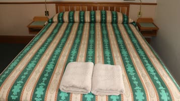 A neatly made bed with a striped bedspread, two bedside tables with lamps, and a folded towel on the bed.