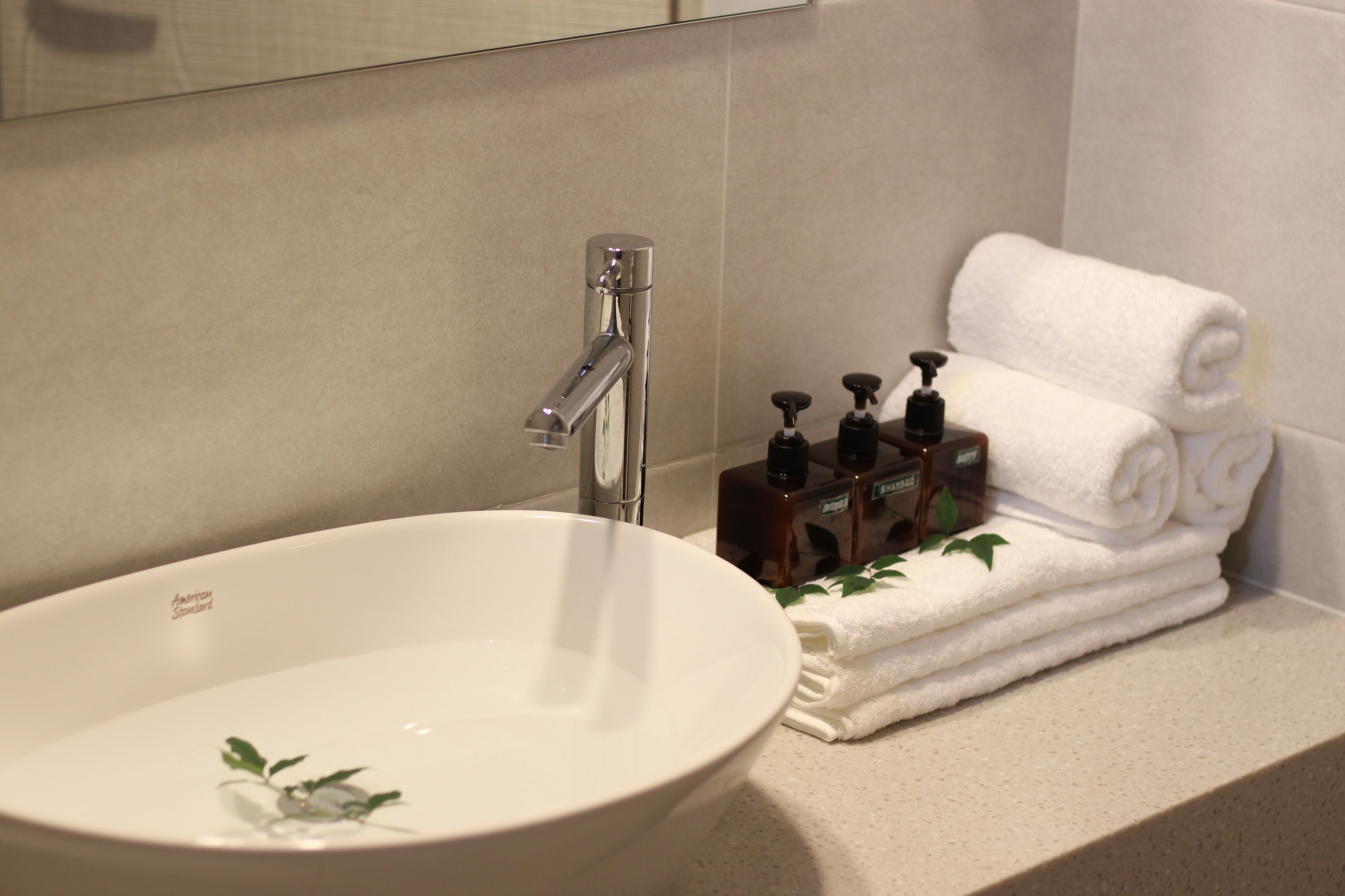 Une salle de bain avec un lavabo blanc, un robinet moderne et des serviettes blanches soigneusement pliées.