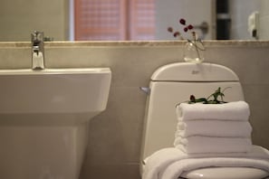 Ett badrum med handfat, toalett och en hög med vita handdukar.