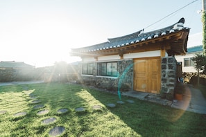 Una casa tradicional coreana con techo de tejas, puerta de madera y muros de piedra.