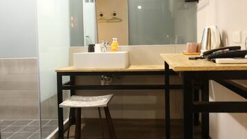 A modern bathroom with a wooden floor, a sink, a mirror, and a bench.