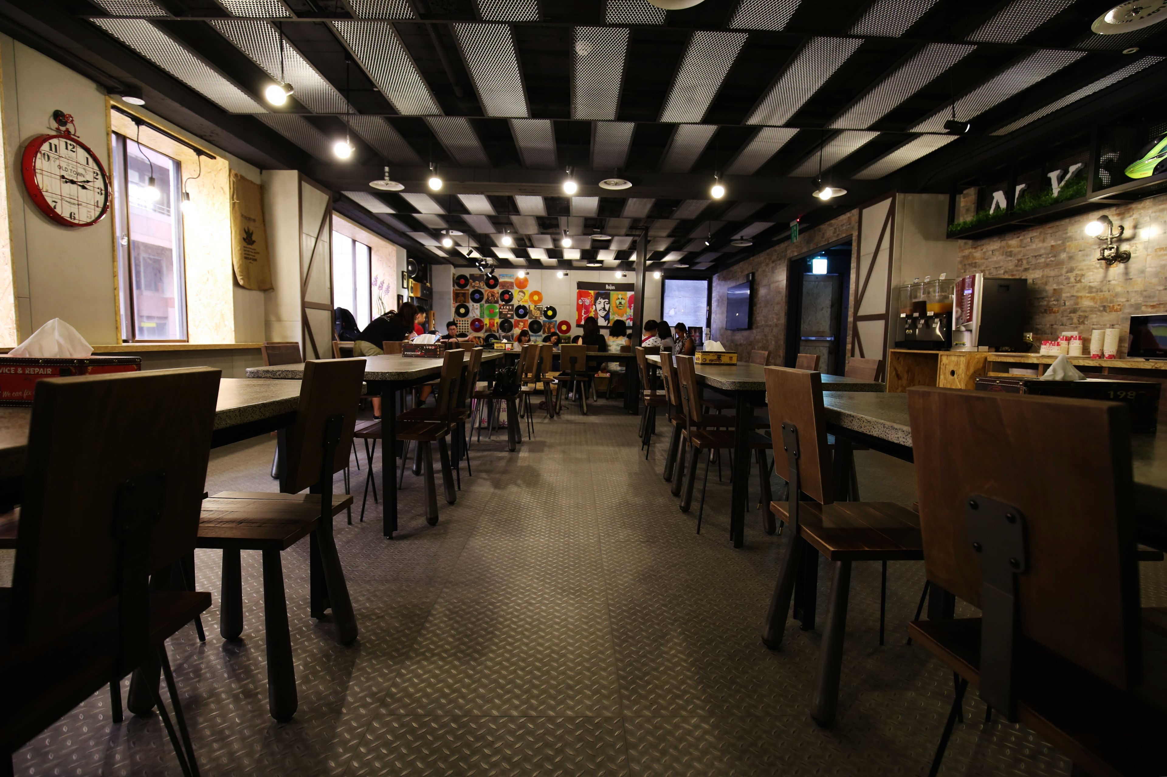A restaurant with a long counter, wooden chairs, and a patterned floor.