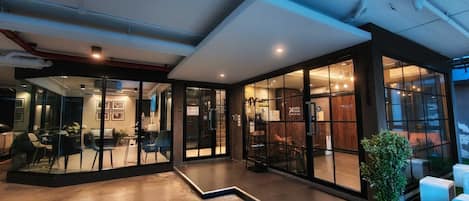 Un interior moderno con puertas de vidrio, una zona de estar y un mostrador de recepción.