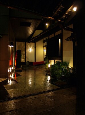 A dimly lit corridor with wet floor, wooden beams, and traditional Japanese-style lighting. - Ryouri Ryokan Watanabe (Nagoya)