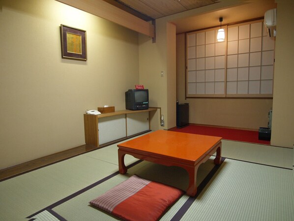 A traditional Japanese room with tatami flooring, a low wooden table, a television on a shelf, and a sliding door with a grid pattern. - Ryouri Ryokan Watanabe (Nagoya)