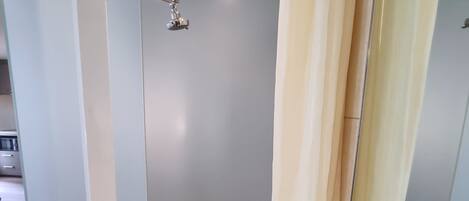 Un baño moderno con ducha, lavamanos y espejo.