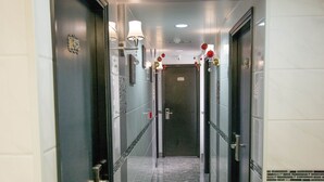 Un pasillo con suelo de mármol, puertas y luces empotradas en la pared.