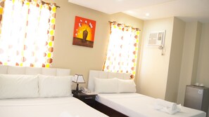 A hotel room with two beds, a painting on the wall, and a small desk with a lamp.