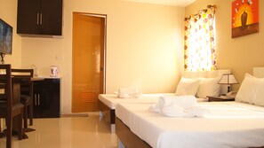 A hotel room with a bed, a desk with a chair, a wardrobe, and a shower area. - Staylite Park B&B (Tagbilaran)