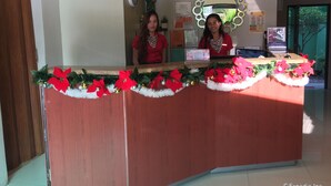 A reception desk with festive decorations, a clock, and informational posters on the wall. - Staylite Park B&B (Tagbilaran)