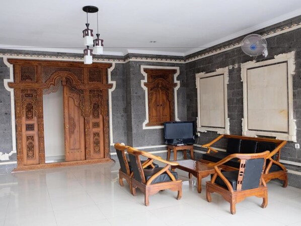 Una stanza con pavimento piastrellato, arredi in legno, una televisione e pannelli decorativi in legno.